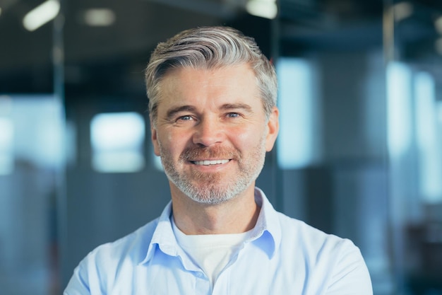 Closeup photo of male businessman portrait of grayhaired experienced man looking at camera and smiling