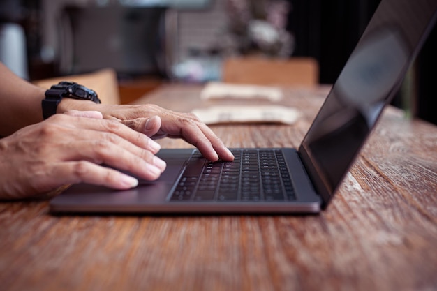 Closeup photo of male hands with laptop businessman working at cafe