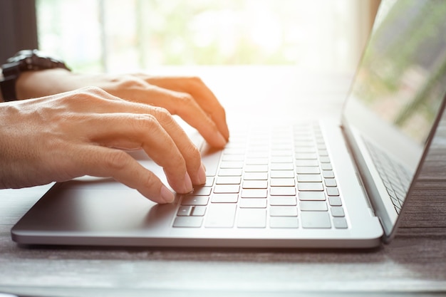 Closeup photo of male hands with laptop businessman working at home office