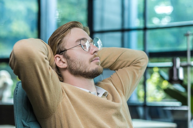 A closeup photo of a man resting in the office a businessman with his hands behind his head with his