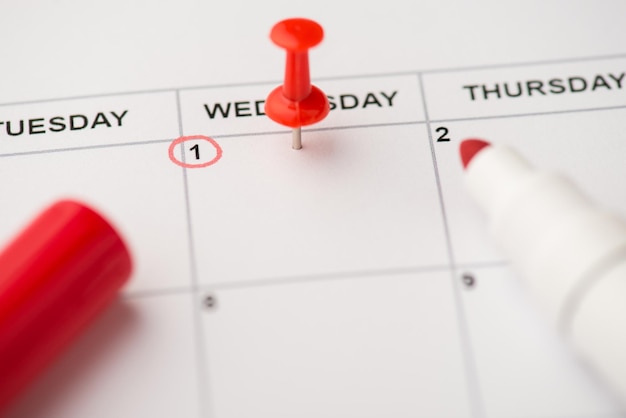 Closeup photo of mark on calendar at wednesday the first with red pushpin and marker with empty space