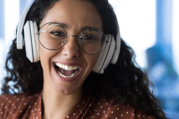 Closeup photo portrait of happy woman wearing glasses smiling and happy listening to music in white