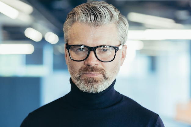 Closeup photo portrait of successful serious and mature businessman investor in glasses looking