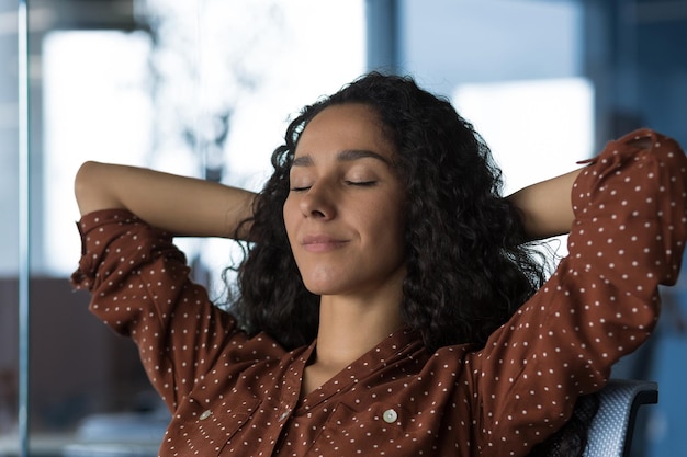 Closeup photo portrait of young beautiful curly arab woman resting indoors at home woman with hands