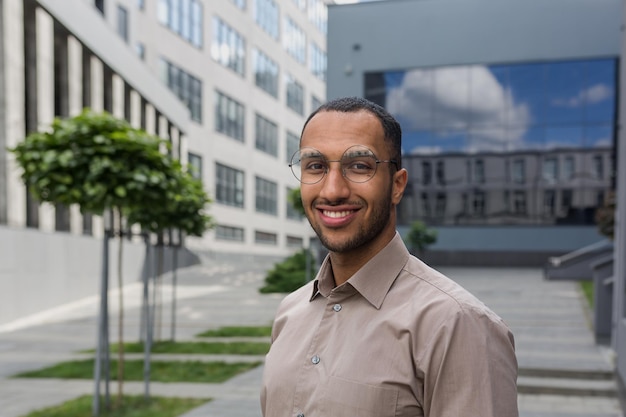 Closeup photo portrait of young entrepreneur wearing glasses hispanic man smiling and looking at