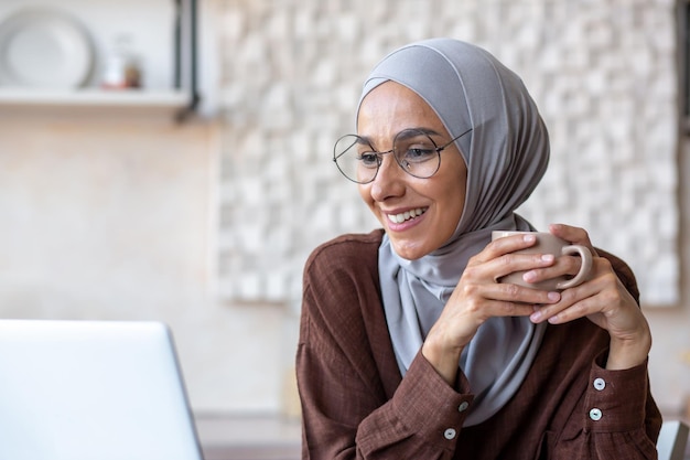 Closeup photo portrait of a young woman of oriental origin in a hijab sitting at home in the kitchen