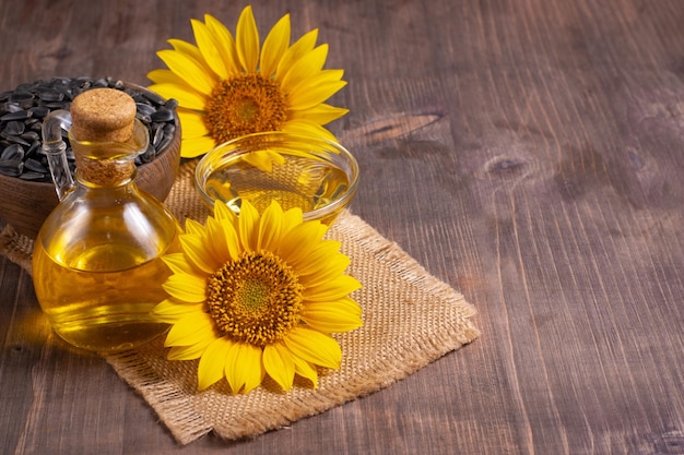 Closeup photo of sunflower oil with seeds on wooden background. Bio and organic product concept.