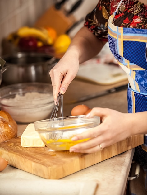 Closeup photo of woman mixing eggs in glass bowl