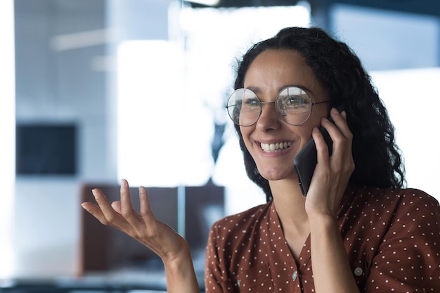 Closeup photo of young beautiful curly arab woman talking on the phone smiling business woman in