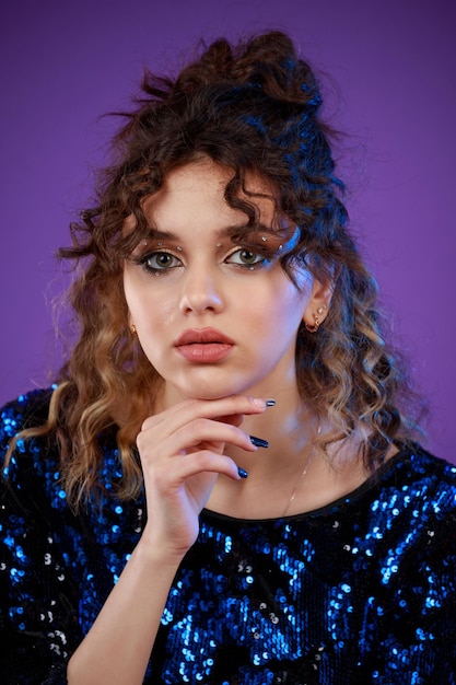 Closeup photo of young curlyhaired girl put her hand to her chon and looking at the camera High quality photo