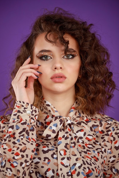 Closeup photo of a young curlyhaired girl putting her hand to her face and looking at the camera High quality photo