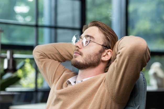 Photo closeup photo young man freelancer student sits on a chair in the office coffee shop and rests he