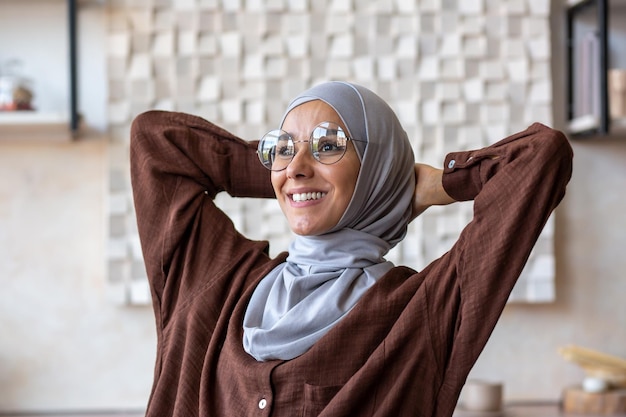 Closeup photo young muslim woman freelancer in hijab sitting at table at home after working day