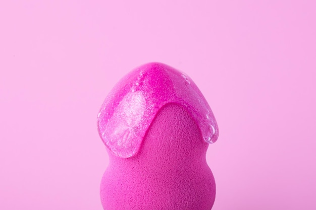 Closeup photography of beauty blender with dripping cosmetic gel on itRaspberry pink background