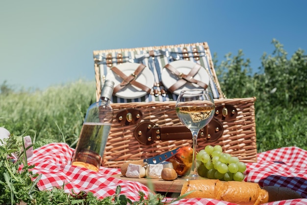 Closeup of picnic basket with drinks and food on the grass