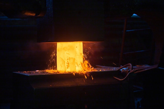 Closeup picture of hot steel manual forging process with big mechanical hammer machine