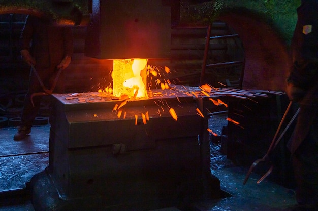 Closeup picture of hot steel manual forging process with big mechanical hammer machine