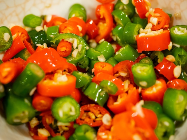 Closeup pieces of chopped red and green chili peppers in bowl, Thai spicy food ingredient