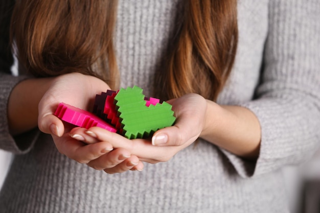 Closeup of plastic puzzle hearts in female hands