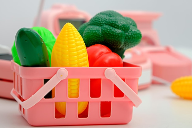 Closeup plastic toy vegetables in pink basket