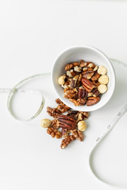 Closeup of a plate with different nuts and a centimeter tape The concept of weight loss healthy eating overweight Fitness menu