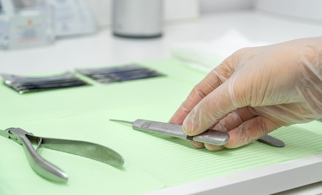 Closeup of a podiatrists hand wearing gloves and taking a gouge from the work table