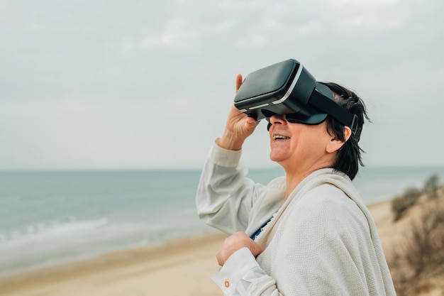 Closeup portrait adult woman on a sandy beach in spring wearing vr virtual reality glasses in front