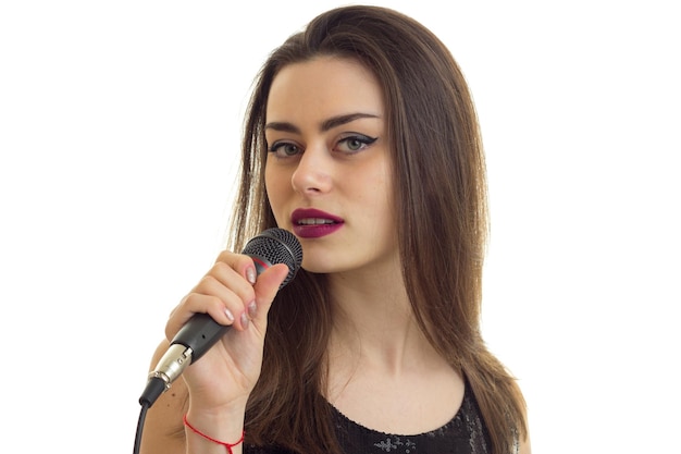 A closeup portrait of attractive young singer with a microphone is isolated on a white background