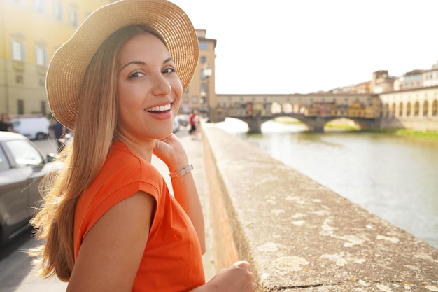 Closeup portrait of attractive young tourist woman who turns around and looking at camera on sunset in Florence Italy