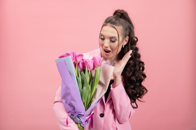 Closeup portrait of an attractive young woman in a jacket holding a bouquet of tulips