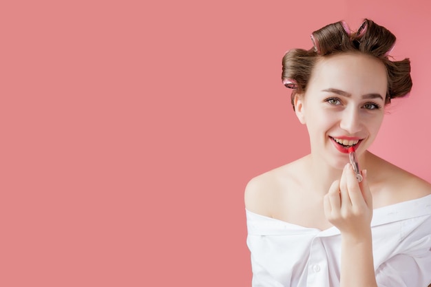 Closeup portrait of beautiful girl putting on red lipstick