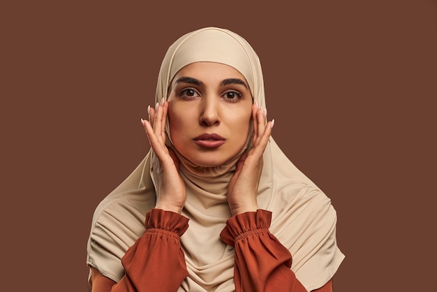 Closeup portrait of beautiful modern muslim woman with natural makeup dressed in beige hijab