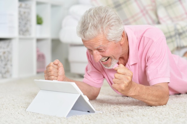 Closeup portrait of beautiful senior man using tablet at home