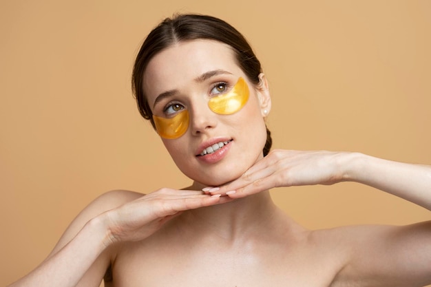 Closeup portrait of beautiful smiling caucasian woman using golden under eye patches