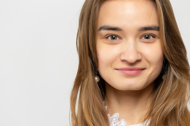 Closeup portrait of a beautiful young girl with dark hair in a studio on a whitegray background