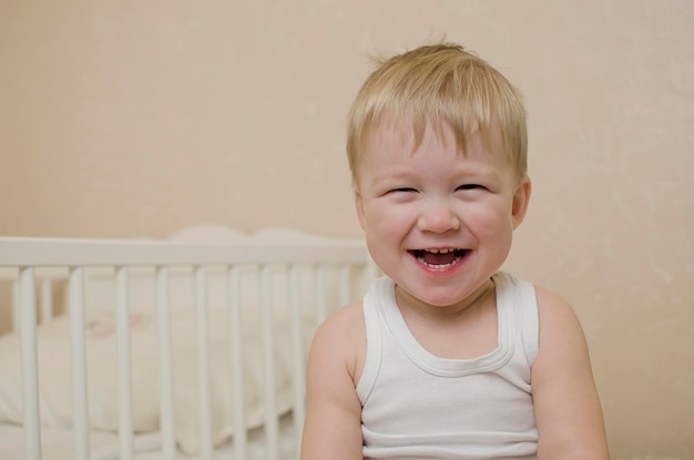 Closeup portrait of a cheerful laughing baby boy in the bedroom