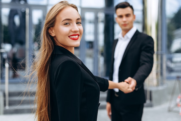 Closeup portrait of cheerful woman on background of office building. Man on blur background - Image