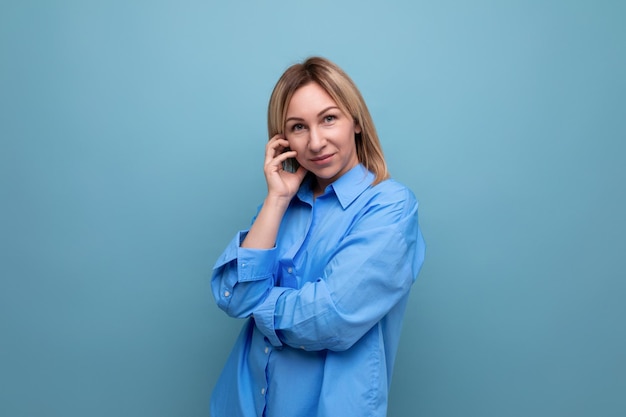 Closeup portrait of a confident attractive blond woman in a shirt on a blue background with