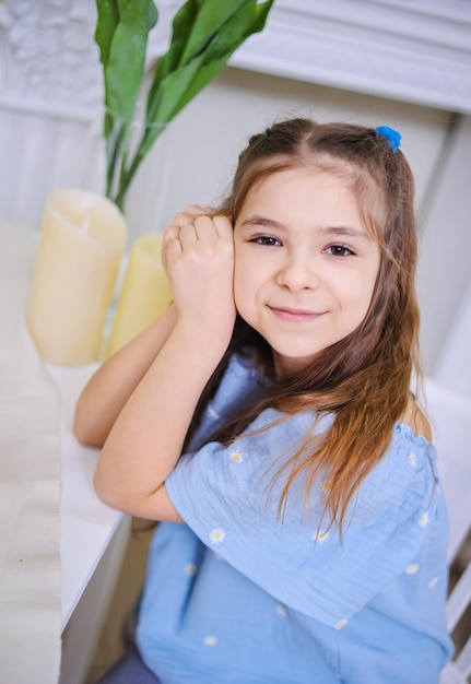 Closeup portrait of a cute girl in a blue blouse sitting against