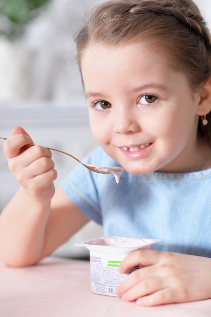 Closeup portrait of cute little girl eating delicious yogurt