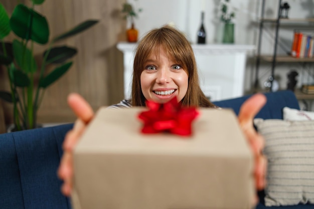 Closeup portrait of a girl showing a gift box to the camera