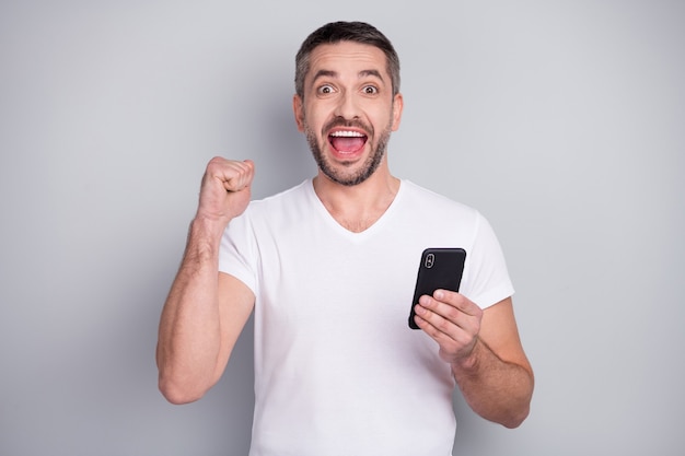 Closeup portrait of glad excited cheery guy using phone celebrate win scream