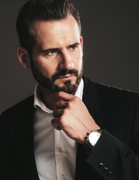 Closeup portrait of handsome confident stylish hipster lambersexual model Sexy modern man dressed in elegant black suit Fashion male posing in studio on dark background