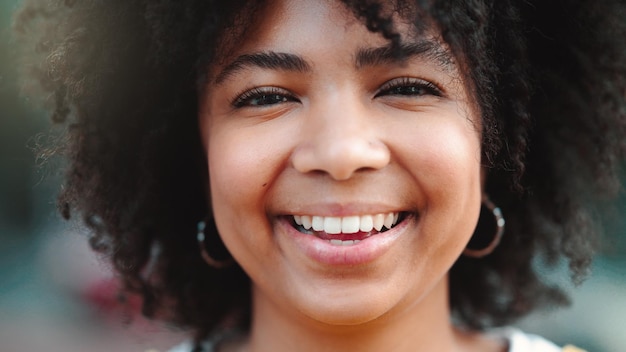 Closeup portrait of a happy female journalism student standing on campus outside Face of a smiling and beautiful woman with an afro commuting to college in the morning Girl laughing at university