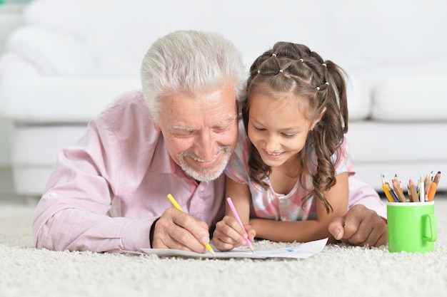 Closeup portrait of happy grandfather with granddaughter drawing together