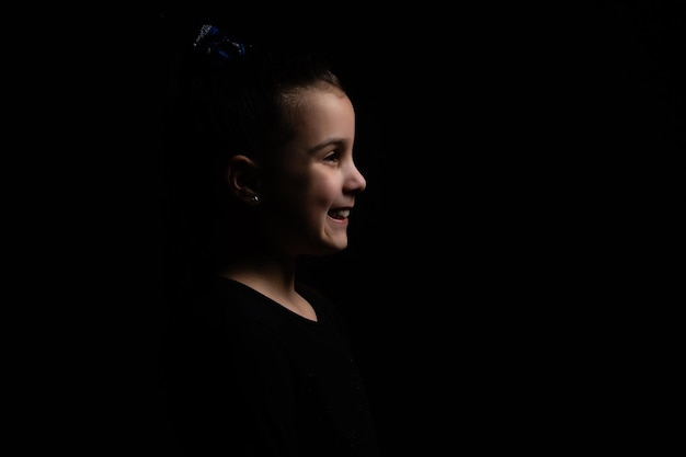 Closeup portrait of happy little girl isolated on black background.