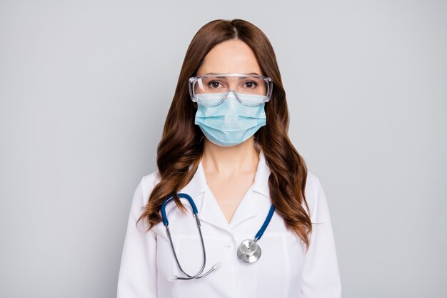 Closeup portrait of her she nice attractive confident skilled experienced wavyhaired doc expert wearing goggles phonendoscope stethoscope hospital service isolated over grey pastel color background