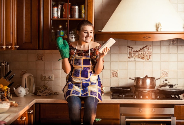 Closeup portrait of housewife sitting on tabletop and using tablet