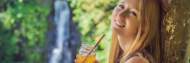 Closeup portrait image of a beautiful woman drinking ice tea with feeling happy in green nature and