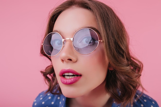 Closeup portrait of lady with pink lips posing with mouth open Indoor photo of stunning european female model in sunglasses isolated on pastel background